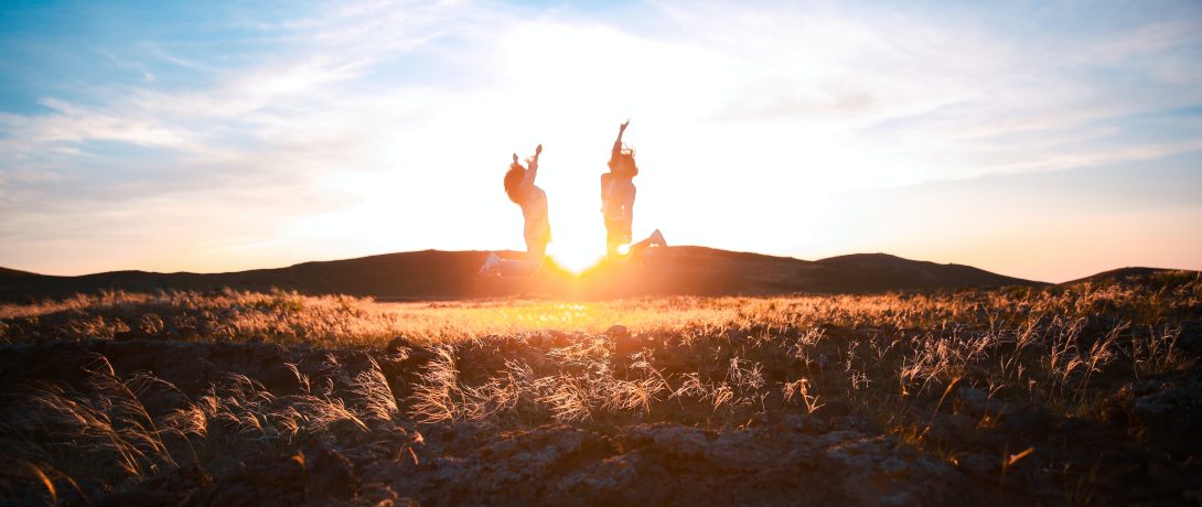 two-women-jumping-on-plant-field-2480526